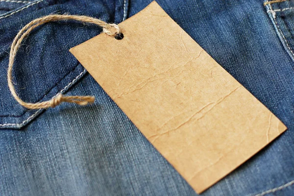 Jeans met blanco papieren prijskaartje — Stockfoto