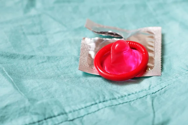 Rosa Kondom auf blauem Bettlaken — Stockfoto