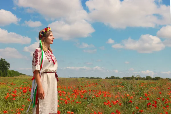 의상을 꽃에서 화환을 우크라이나 소녀가 양귀비와 하늘을 배경으로 우크라이나 애국심을 — 스톡 사진
