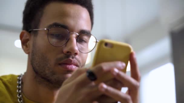 락 포커스: 스마트폰의 근접 사진 과 안경을 낀 젊은 아프리카인의 얼굴 — 비디오