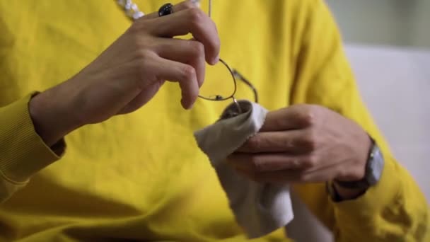 An African American mans hands clean the lenses of his glasses with a microfiber — Stock Video