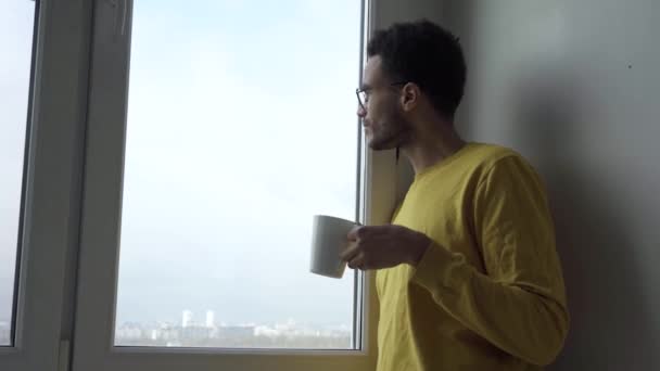 En la ventana un joven con una taza — Vídeos de Stock