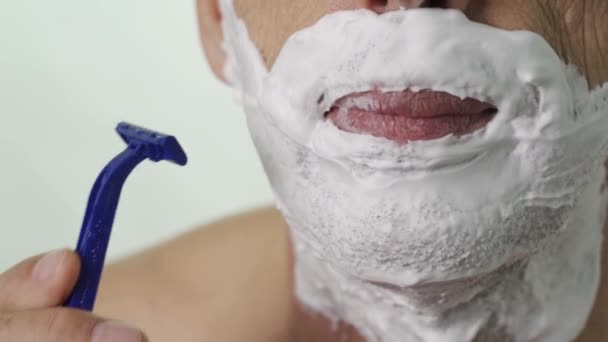 Close-up of an elderly mans chin shaving with a disposable razor — Stock Video