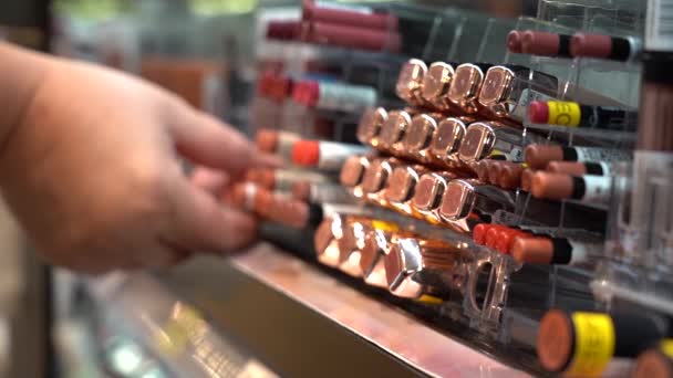 Primer plano de las manos de las mujeres la elección de lápiz labial en una tienda de cosméticos — Vídeos de Stock