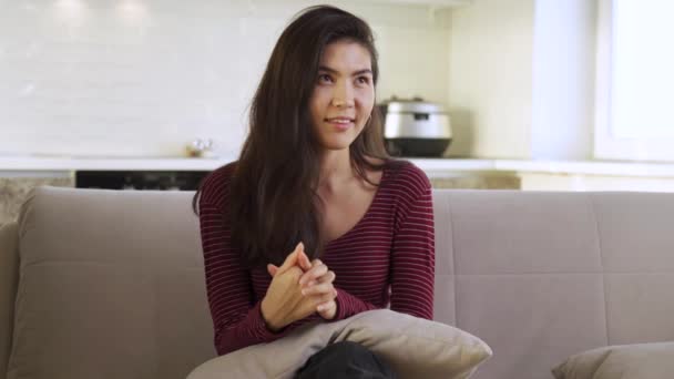 Portrét šťastné asijské dívky sedící doma na gauči — Stock video