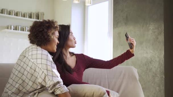 Heureuses jeunes deux copines, une afro-américaine et une asiatique, prennent des selfies dans leur maison — Video