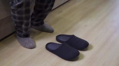 Pijamalı bir adam ayaklarına terlik giymiş.
