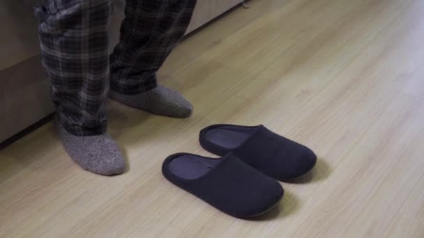 Un hombre en pijama lleva zapatillas de casa en los pies. — Vídeos de Stock
