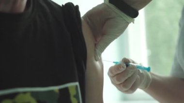 Kadın bir doktor yaşlı bir adamı koronavirüse karşı aşılıyor..