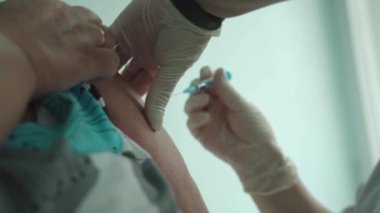 Kadın bir doktor yaşlı bir adamı koronavirüse karşı aşılıyor..