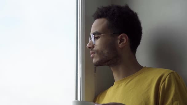 En la ventana un joven con una taza — Vídeos de Stock