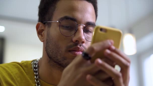 Ein afrikanischer junger Mann benutzt ein Smartphone. — Stockvideo