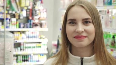 Süpermarkette mutlu, genç bir kadın. Kameraya bak