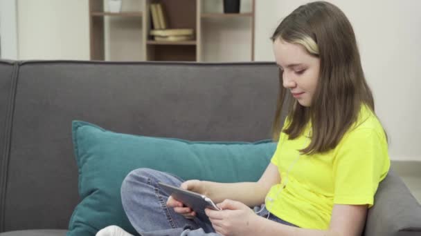 Щаслива дівчина з Кавказу на зручному дивані дивиться фільм на своїй дощечці. — стокове відео