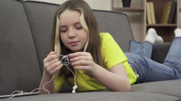 Adolescente démêler les fils des écouteurs filaires — Video