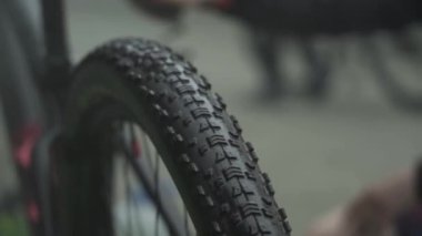 Bir sporcu, dağ bisikletini bir hortumun musluğunun altında yıkıyor.