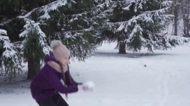 Mutlu bir genç kız havaya taze kar fırlatıyor.