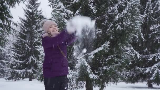 SLOW MOTION: Een gelukkig tienermeisje gooit verse sneeuw in de lucht — Stockvideo