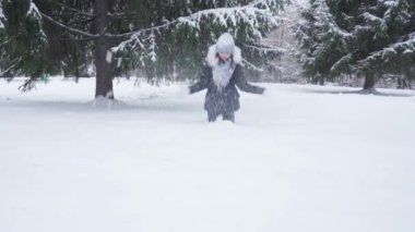 Genç kız parkta oynarken taze kar atıyor.