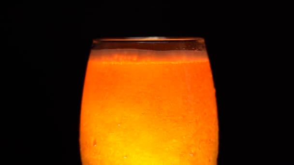 Häll lätt öl i ett glas på en mörk bakgrund. Inre glöd — Stockvideo