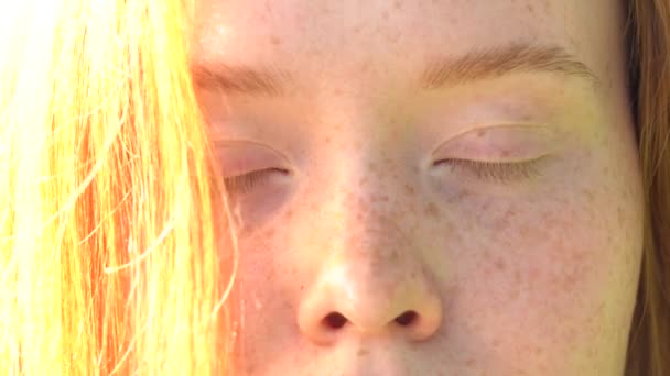 Portret van een lachende jonge vrouw met rood haar en sproeten tegen de achtergrond van een heldere, zonnige weide. Natuurlijke schoonheid met sproeten — Stockvideo