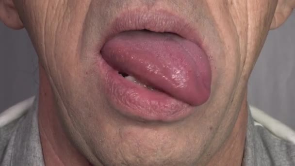 Het uitsteken van de tong op het gezicht van een oudere blanke man — Stockvideo