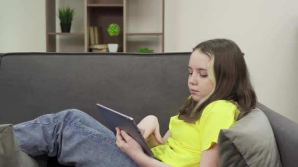 En tonårstjej som använder surfplatta hemma — Stockvideo