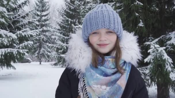 Портрет щасливої, блакитноокої дівчини-підлітка в засніженому парку — стокове відео