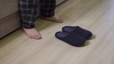 Pijamalı bir adam ayaklarına terlik giymiş.