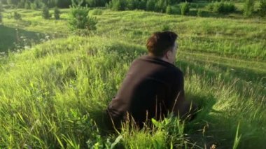 Uzun otların arasından, oturan bir adamın siluetine bak..