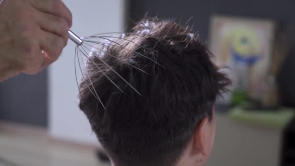 Een man masseert zijn eigen hoofdhuid met een scalp massager — Stockvideo