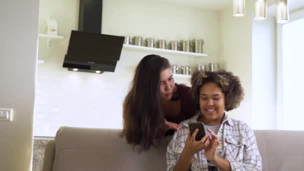Happy girlfriends looking at a smartphone together while at home — Stock Video