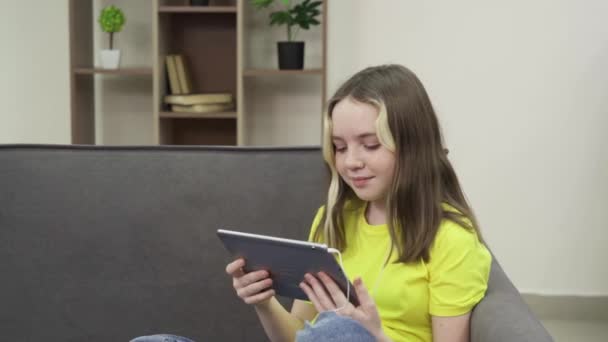 Una bambina guarda cartoni animati su una tavoletta — Video Stock