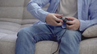 Evde joystick ile video oyunu oynayan tanınmayan genç adam.