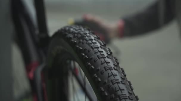 Un atleta lava su bicicleta de montaña bajo un grifo de agua de una manguera — Vídeos de Stock