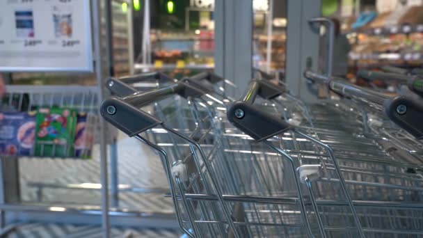 Prenez un chariot d'épicerie pour faire du shopping. Gros plan Acheteur à main masculin tirant son panier de la rangée dans un supermarché ou une épicerie — Video