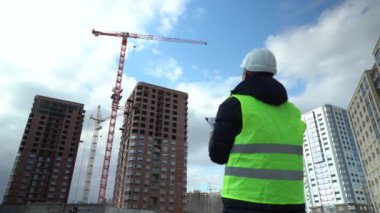 Consulting engineer at construction site holding blueprint in hand. Construction inspector