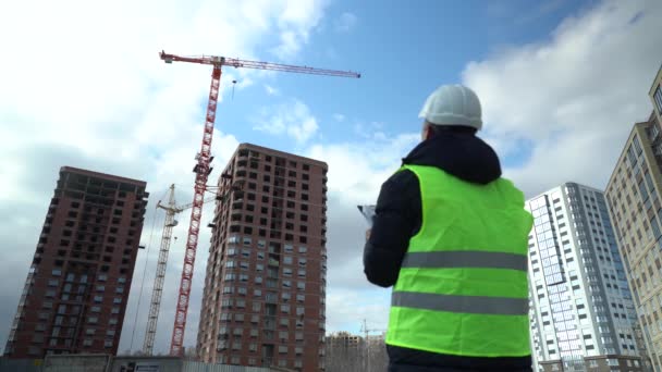 Consulting engineer at construction site holding blueprint in hand. Construction inspector — Vídeo de stock