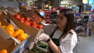 Genç bir satıcı kız bir süpermarketin yemek salonunda taze sebzeler hazırlıyor.