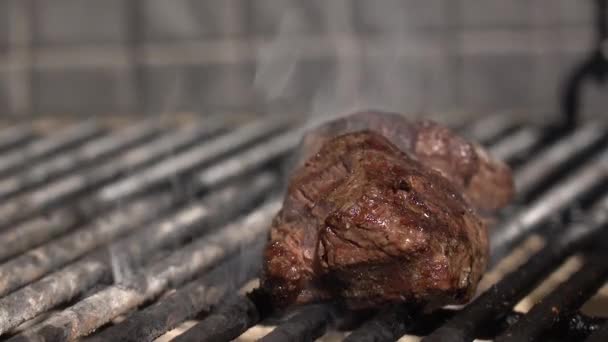 Філет Міньйон. Смачний яловичий стейк смажить на решітці гриля на тлі палаючого вогню — стокове відео