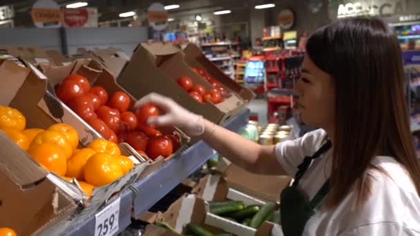 Genç bir satıcı kız bir süpermarketin yemek salonunda taze sebzeler hazırlıyor. — Stok video