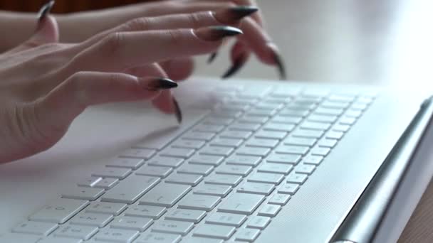 Žena ruce ženy psaní na klávesnici notebooku, zatímco sedí u svého stolu — Stock video