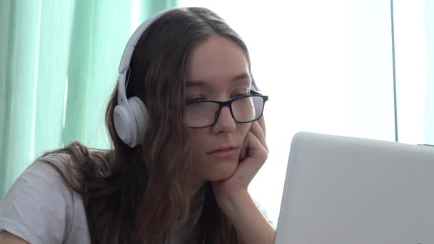 Sérieux caucasien fille portant casque et regarder un cours vidéo éducatif avec son ordinateur portable — Video