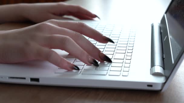 Vrouwelijke handen van een vrouw typen op een laptop toetsenbord terwijl zitten aan haar bureau — Stockvideo