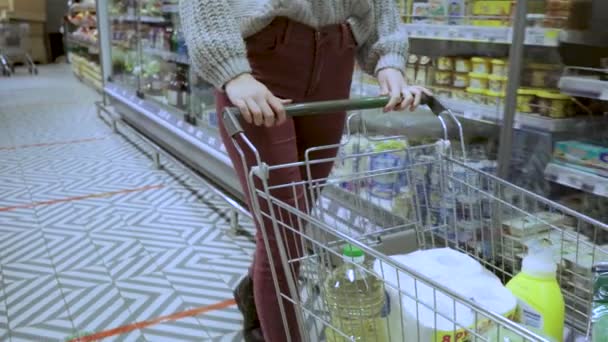 Primer plano de un joven manos de mujer moviendo un carrito de comestibles a través de los pasillos de un supermercado, el concepto de venta y compras — Vídeos de Stock