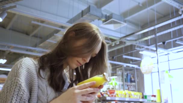 Seorang pelanggan wanita muda membaca komposisi minuman pada botol jus — Stok Video
