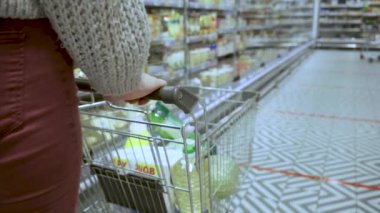 Genç bir kadının elleri süpermarketin koridorlarında market arabasını taşırken, satış ve alışveriş konsepti