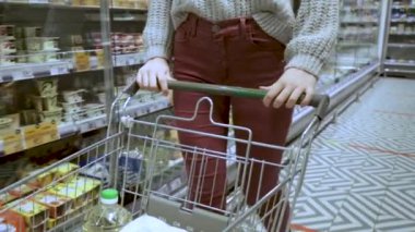 Genç bir kadının elleri süpermarketin koridorlarında market arabasını taşırken, satış ve alışveriş konsepti