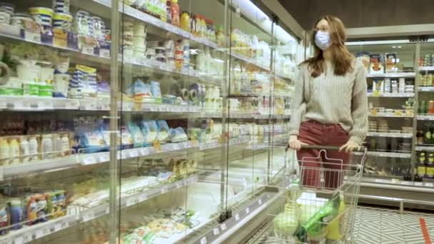 Närbild av en ung kvinna händer flytta en matvagn genom gångarna i en stormarknad, begreppet försäljning och shopping — Stockvideo