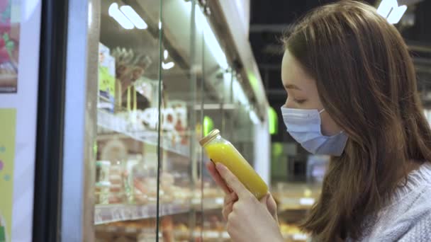 Genç bir bayan müşteri meyve suyu şişesindeki içkinin bileşimini okuyor. — Stok video